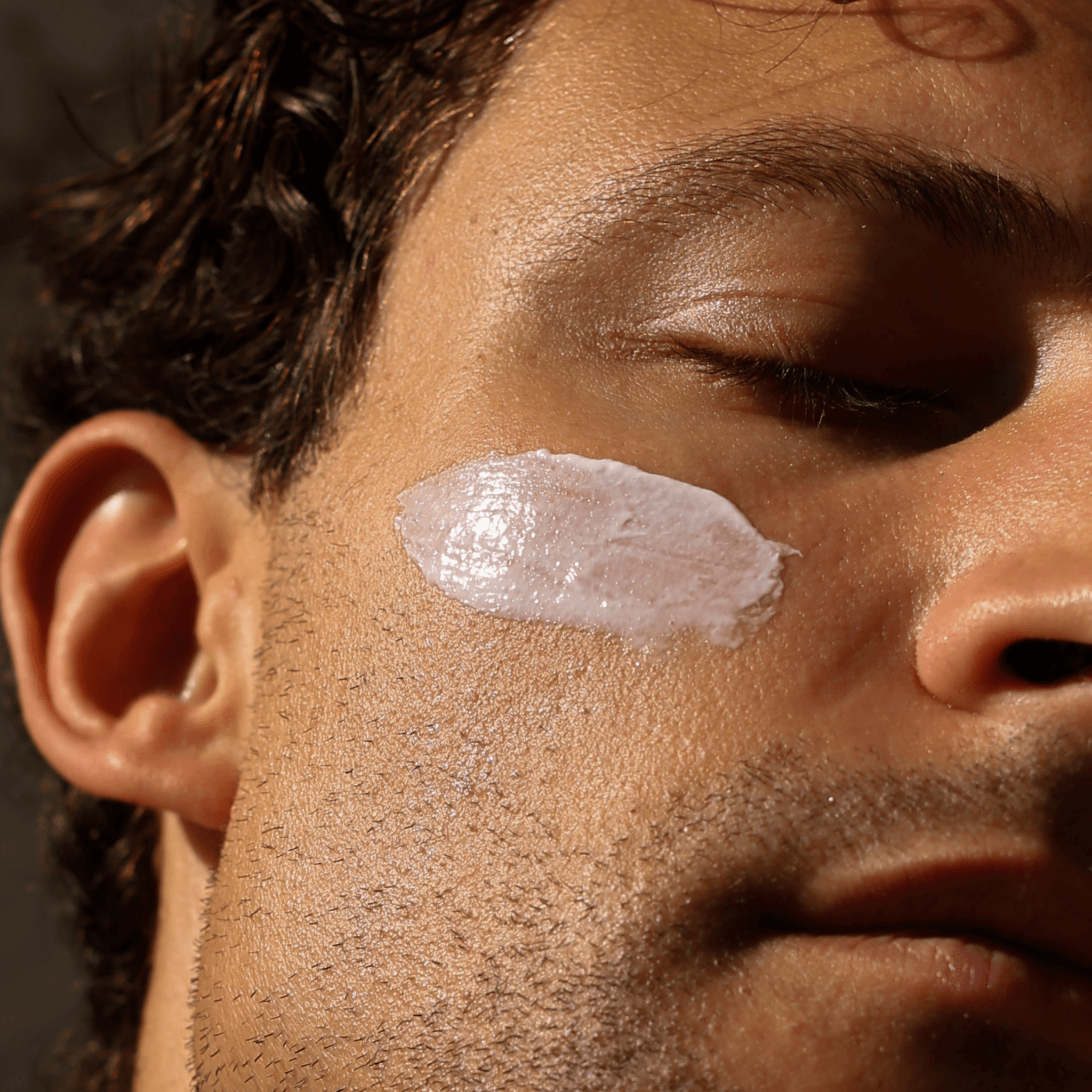 Nahaufnahme des Gesichts einer Person mit geschlossenen Augen, auf deren Wange DALUMA FACIAL MOISTURIZER GESICHTSPFLEGE verschmiert ist, um die natürliche Feuchtigkeit und die sanfte Anwendung der Hautpflege hervorzuheben.