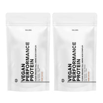 Zwei weiße, wiederverschließbare Beutel mit DALUMA VEGANES PERFORMANCE PROTEIN KAKAO DOUBLE stehen aufrecht und präsentieren diese vegane Bio-Proteinmischung mit minimalistischem schwarzem Text und dem Hinweis 