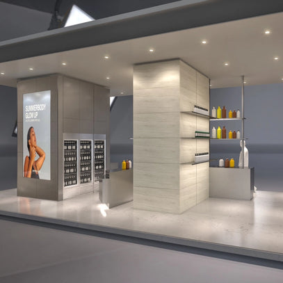 Ein moderner, offen gestalteter Verkaufsraum mit hellen Wänden, Regalen mit Flaschen und einer Theke. Ein großes Plakat mit einer Frau und dem Text "SUMMERBODY GLOW UP" ist an einer Wand zu sehen.