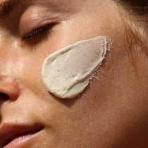 Eine Nahaufnahme des Gesichts einer Person mit geschlossenen Augen, auf deren Wange die DEEP HYDRATION FEUCHTIGKEITSMASKE von DALUMA aufgetragen ist - eine dicke, cremige Maske aus natürlichen Zutaten.