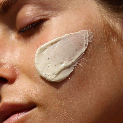 Eine Nahaufnahme des Gesichts einer Person mit geschlossenen Augen und einer großzügigen Schicht DALUMA DEEP HYDRATION FEUCHTIGKEITSMASKE, hell mit winzigen Tupfen, auf der Wange - um die natürlichen Inhaltsstoffe zu zeigen.