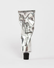 Eine zerknitterte silberne Tube mit schwarzer Kappe, auf der FACIAL MOISTURIZER GESICHTSPFLEGE und DALUMA steht, ruht auf einem schlichten weißen Hintergrund - eine elegante Feuchtigkeitscreme für das Gesicht und natürliche Feuchtigkeitscreme für jeden Hauttyp.