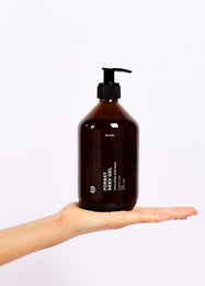 Eine Hand hält eine große braune Pumpflasche mit der Aufschrift FOREST SEED GEL HAND WASH von DALUMA, zentriert vor einem schlichten weißen Hintergrund. Diese Handseife mit natürlichen Inhaltsstoffen ist ideal für sanfte Hautpflege.
