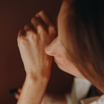 Nahaufnahme von Gesicht und Hand einer Person, das Kinn auf der geballten Faust, vor einem schummrigen Hintergrund - mit NULLPUNKT GRADE 0.2 RELEASE von Nullpunkt.