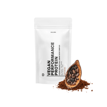 Ein weißer DALUMA VEGANES PERFORMANCE PROTEIN KAKAO-Beutel mit schwarzer Schrift und wiederverschließbarem Deckel steht aufrecht neben einer mit Bohnen und rohem Kakao gefüllten Kakaoschote und hebt den pflanzlichen Eiweißgehalt in einer minimalistischen Verpackung hervor.